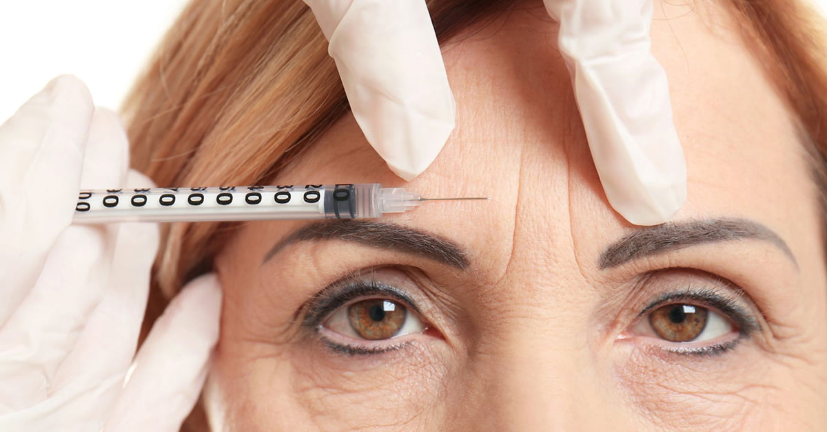 A woman is getting a neurotoxin injection for her eyebrows at work.
