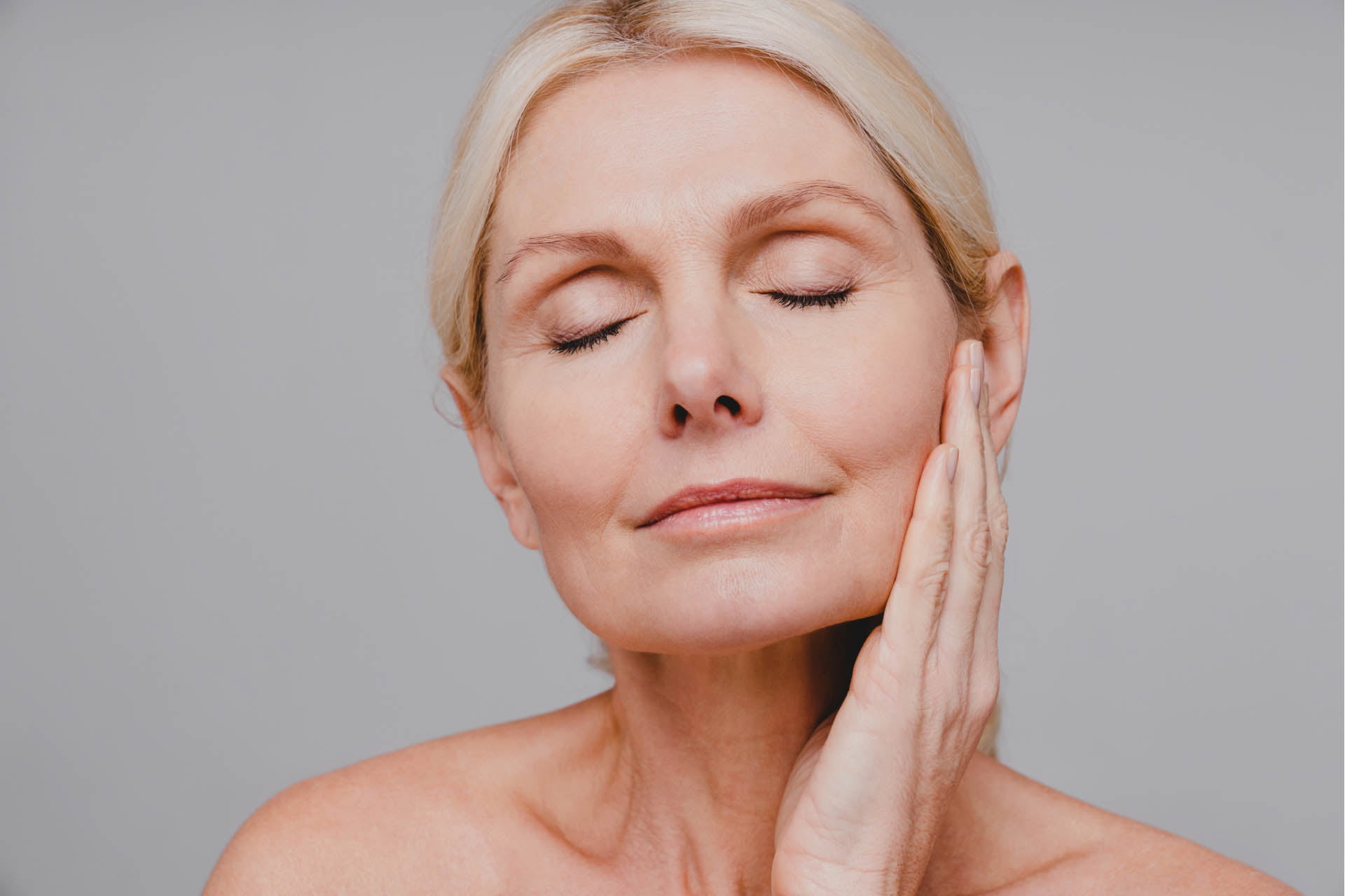 A woman at Skin Suite Atlanta Medspa in Brookhaven GA with her hands on her face after a treatment.