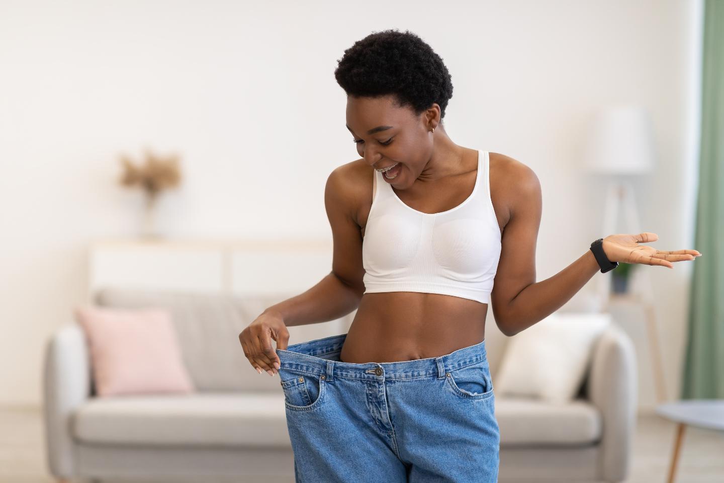 Young african american woman checking her weight at home.