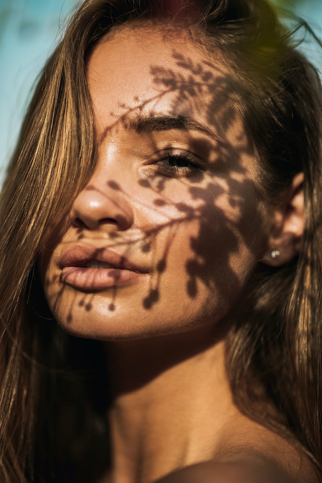 A woman's face with a faint shadow of a tree.