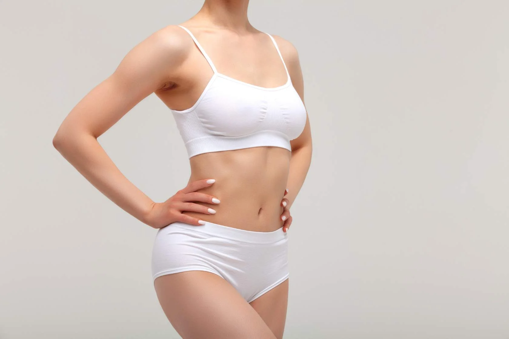 A woman in a white bikini posing on a gray background for modeling services.