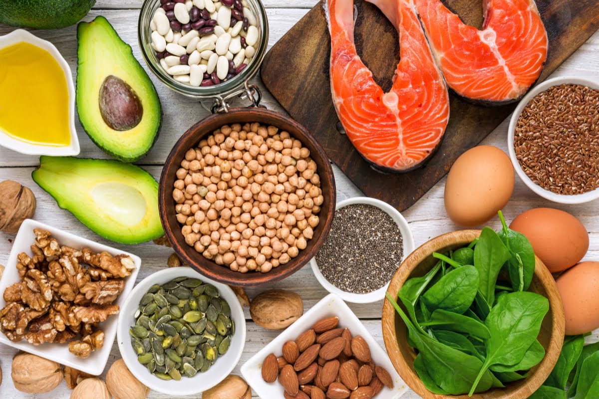 Assorted foods for healthy skin, rich in protein and omega-3 fatty acids displayed on a wooden table.