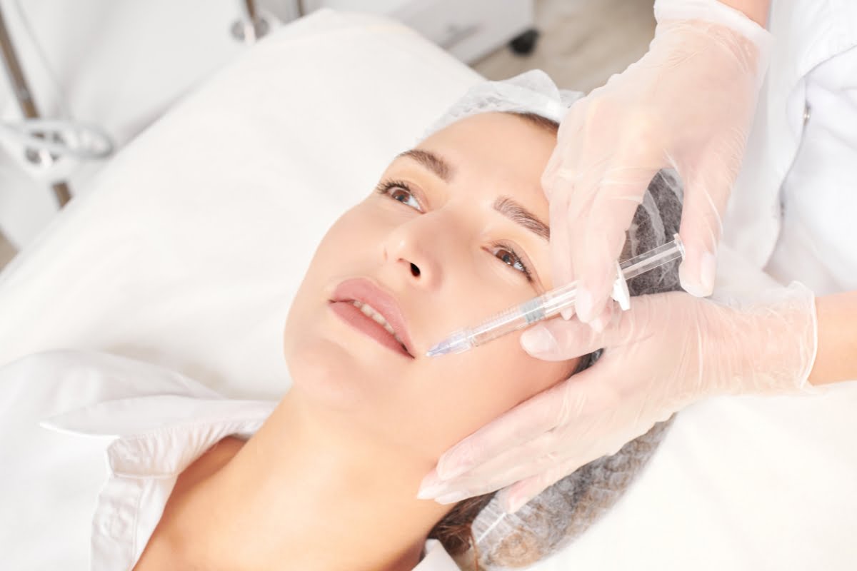 Aesthetician administering a neurotoxin treatment to a female patient in a clinical setting.