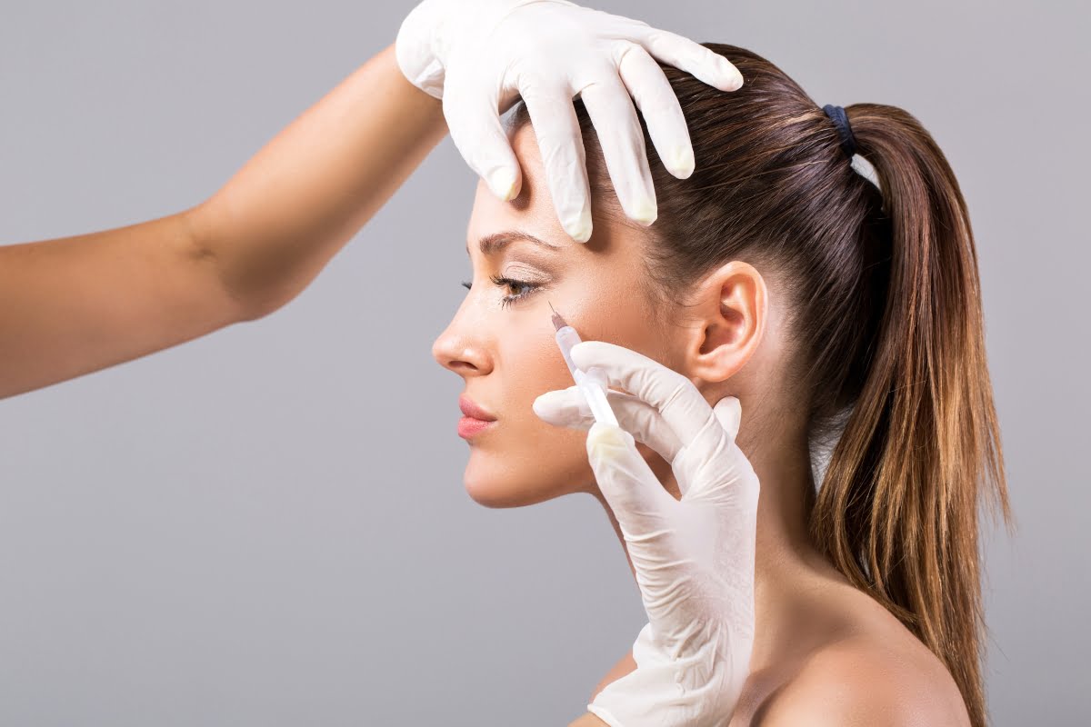 Aesthetic professional in gloves examining a woman's facial skin for the benefits of Botox.