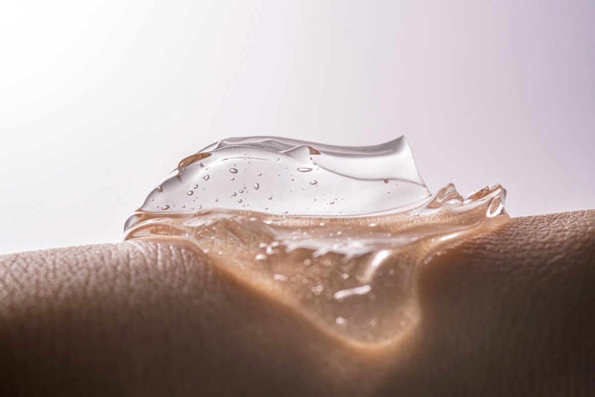 Close-up of a transparent gel with bubbles on textured skin. The light illuminates the gel, highlighting its smooth and glossy appearance, enhancing skin elasticity.