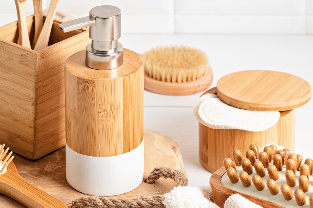 A neatly arranged collection of wooden bathroom accessories, including a soap dispenser, brushes, and containers on a light-colored surface, adds an eco-friendly touch to your sustainable skin care routine.